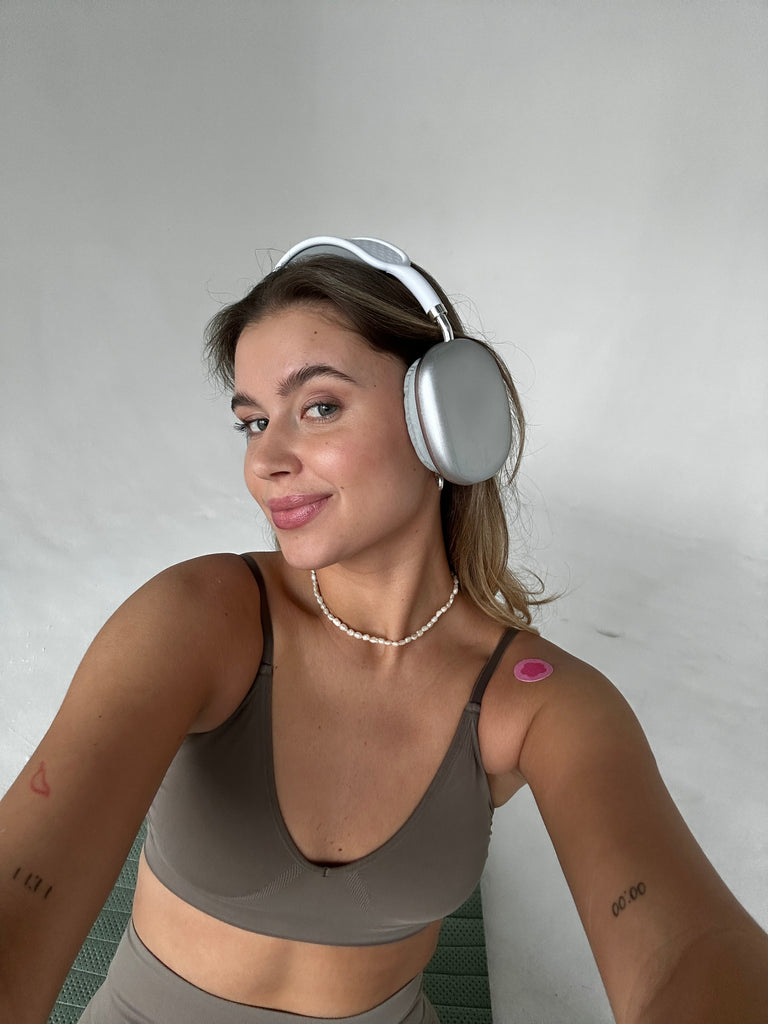 Girl with headphones and a wellness patch on her shoulder