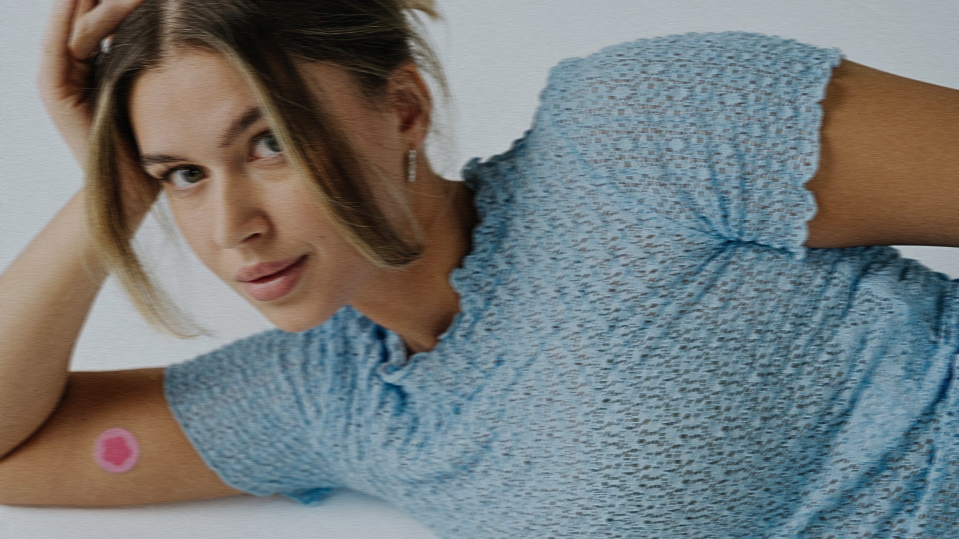 Relaxed girl laying down with a period patch on her arm
