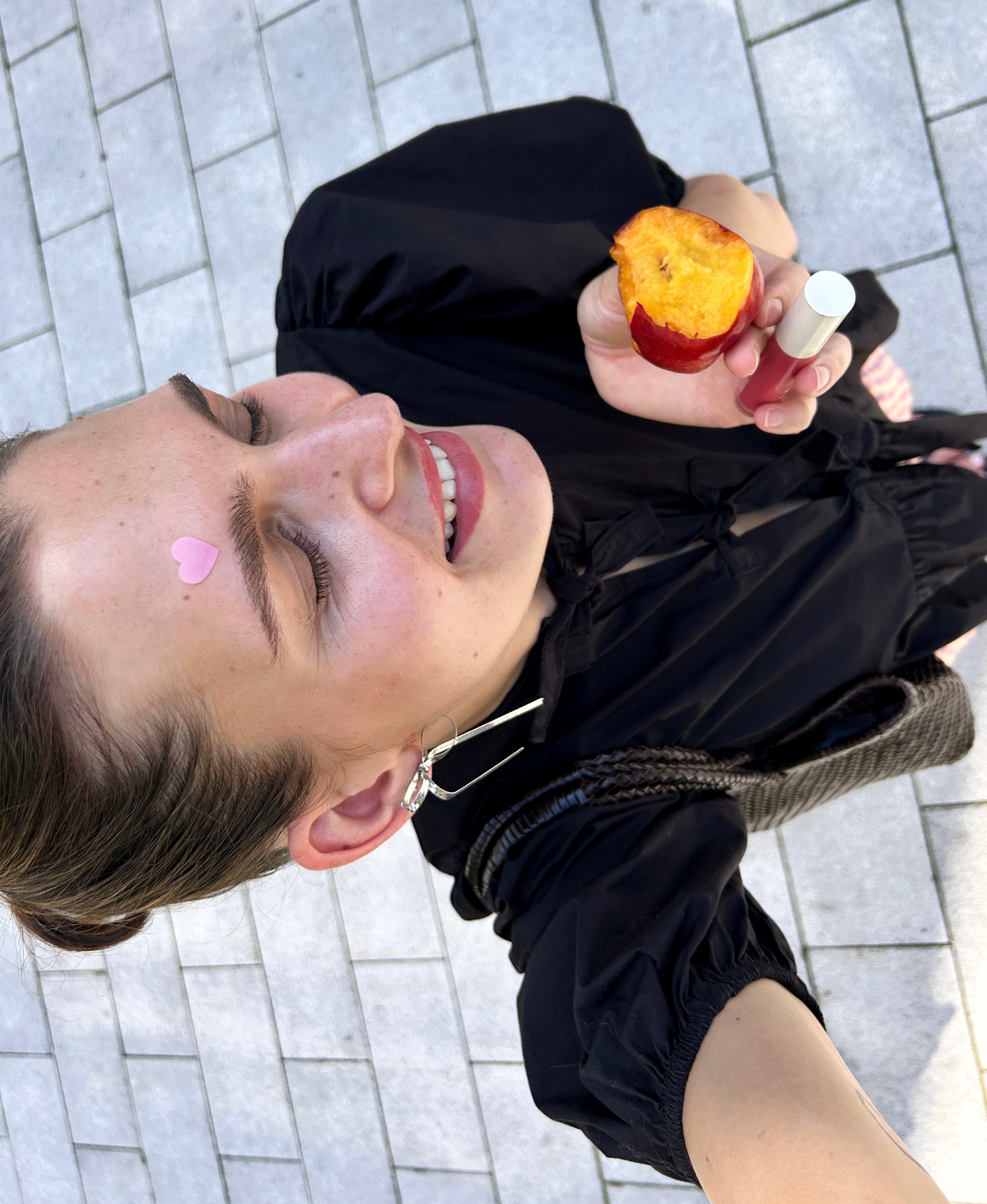 Happy girl eating a peach with a heart shaped spot patch on her forehead
