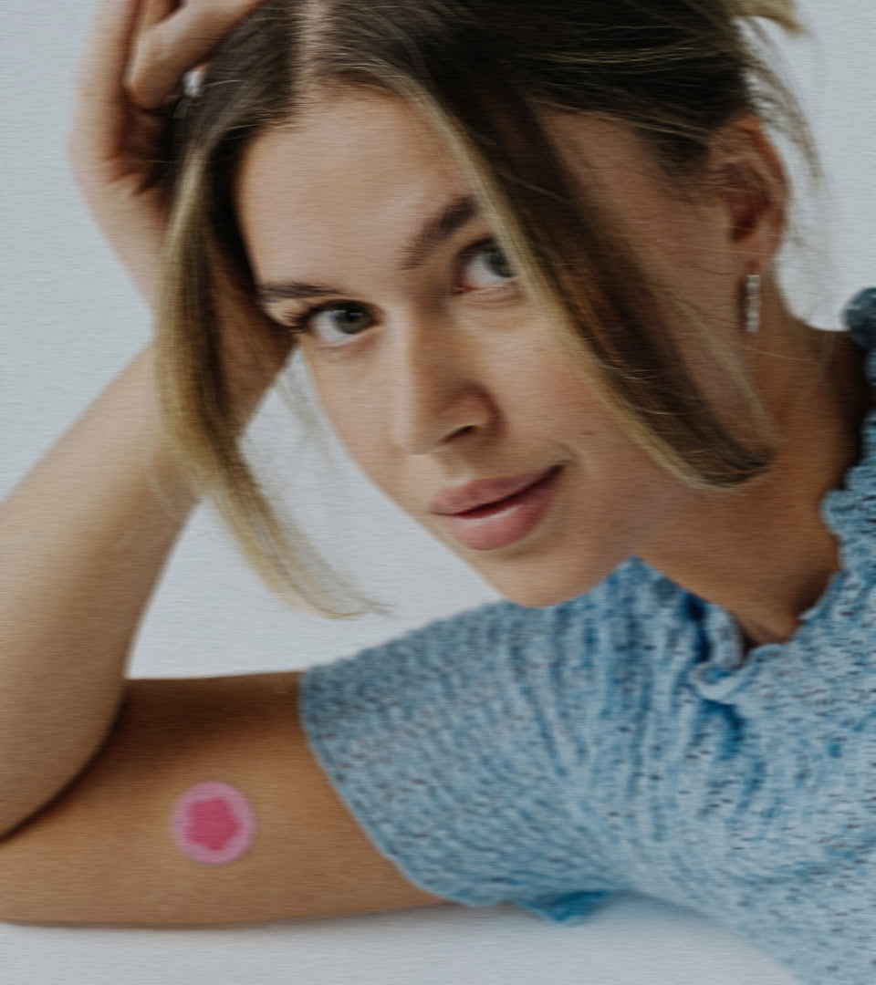 Relaxed girl laying down with a period patch on her arm