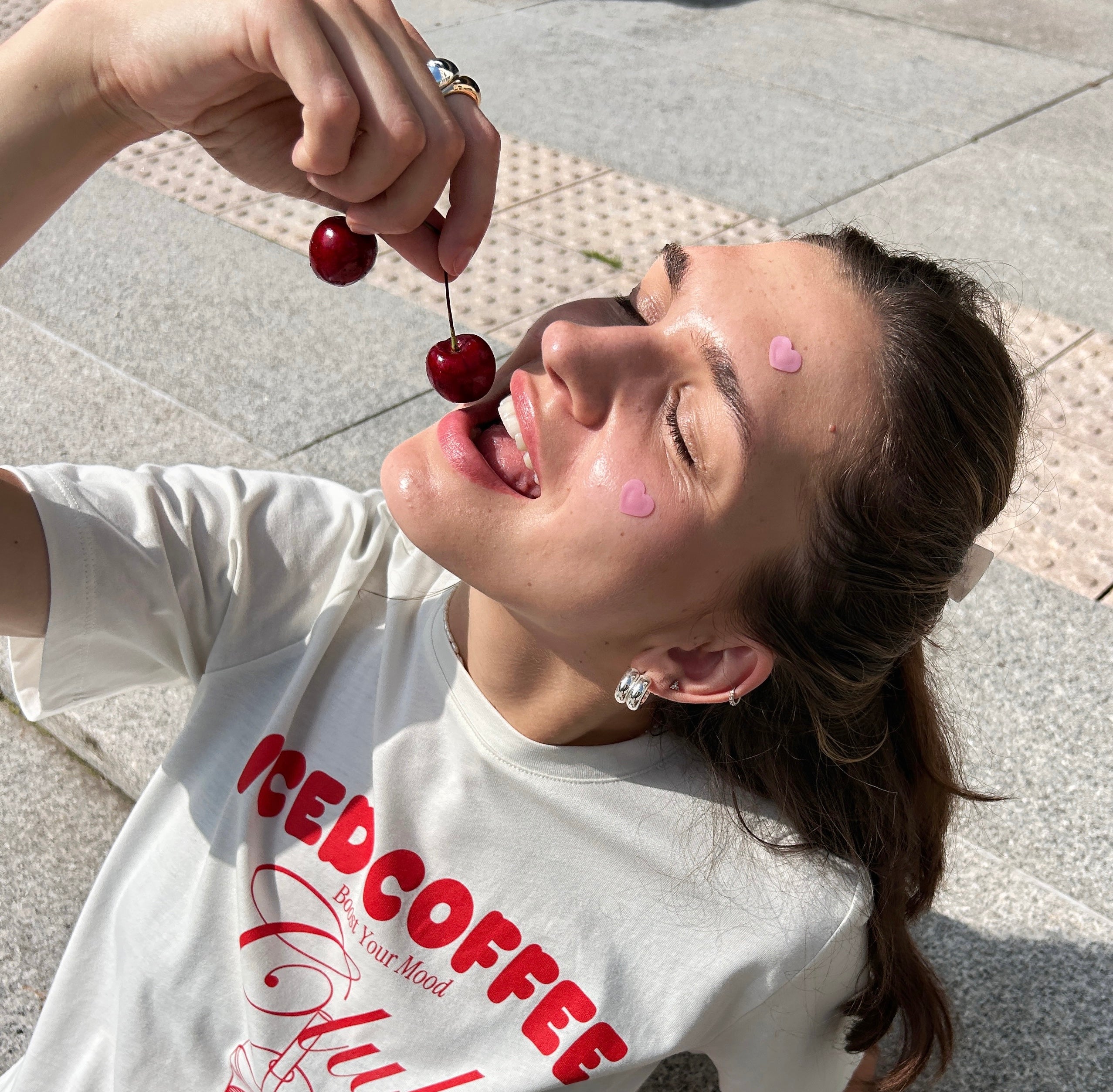 girl eating cherries, wearing heart-shaped microneedle spot patches